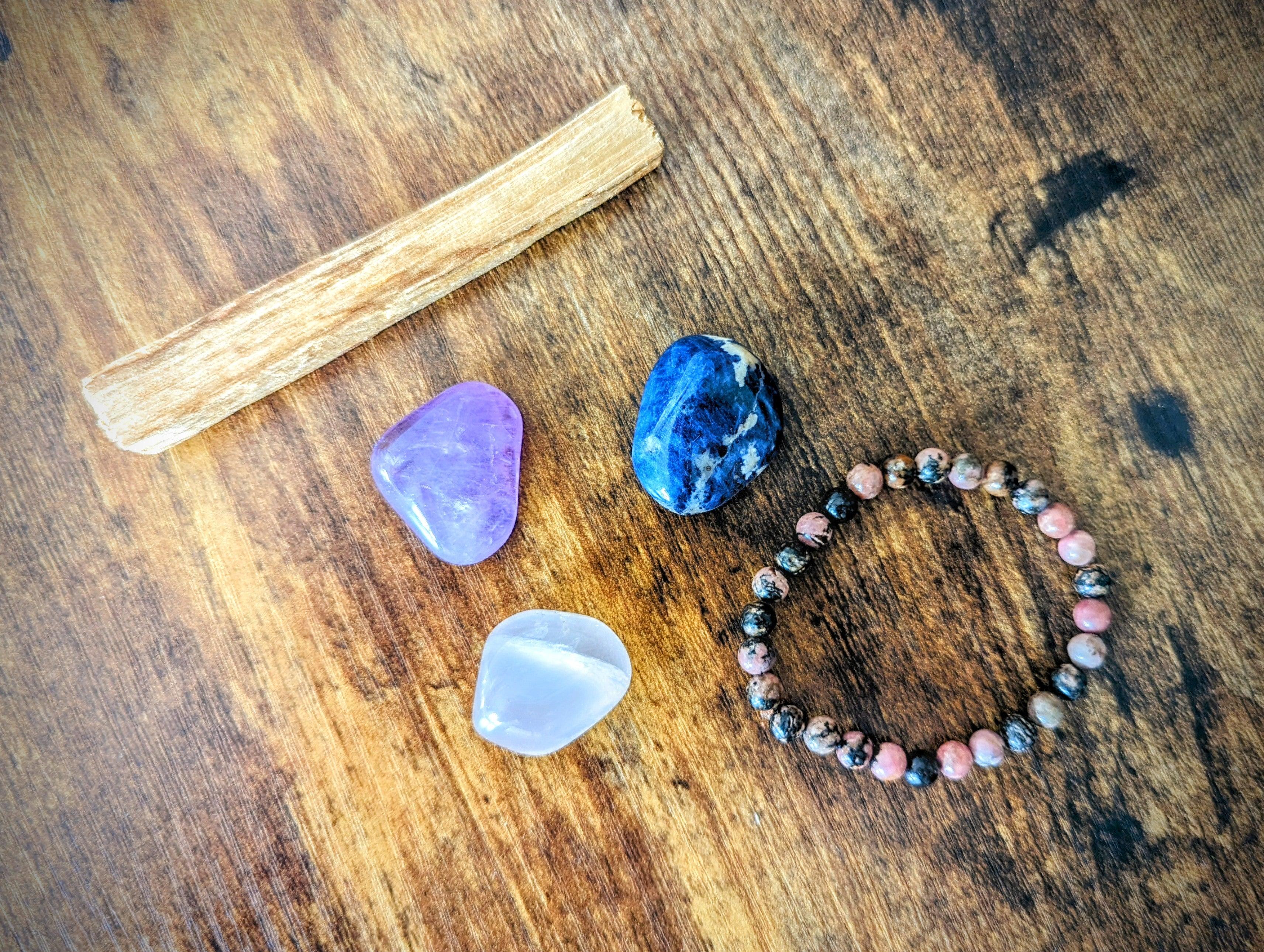pierres d'améthyste quartz rose et sodalite avec un bracelet de rhodonite et un bois de palo santo composant le kit anti-stress